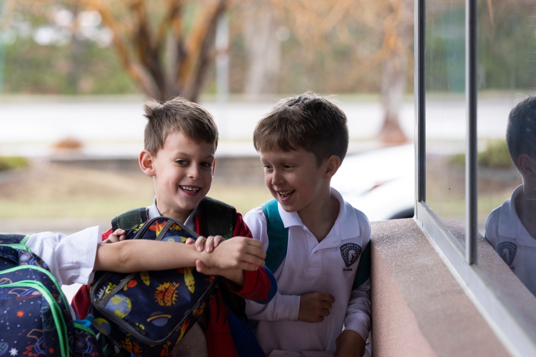 Two young elementary boys smile and laugh together.